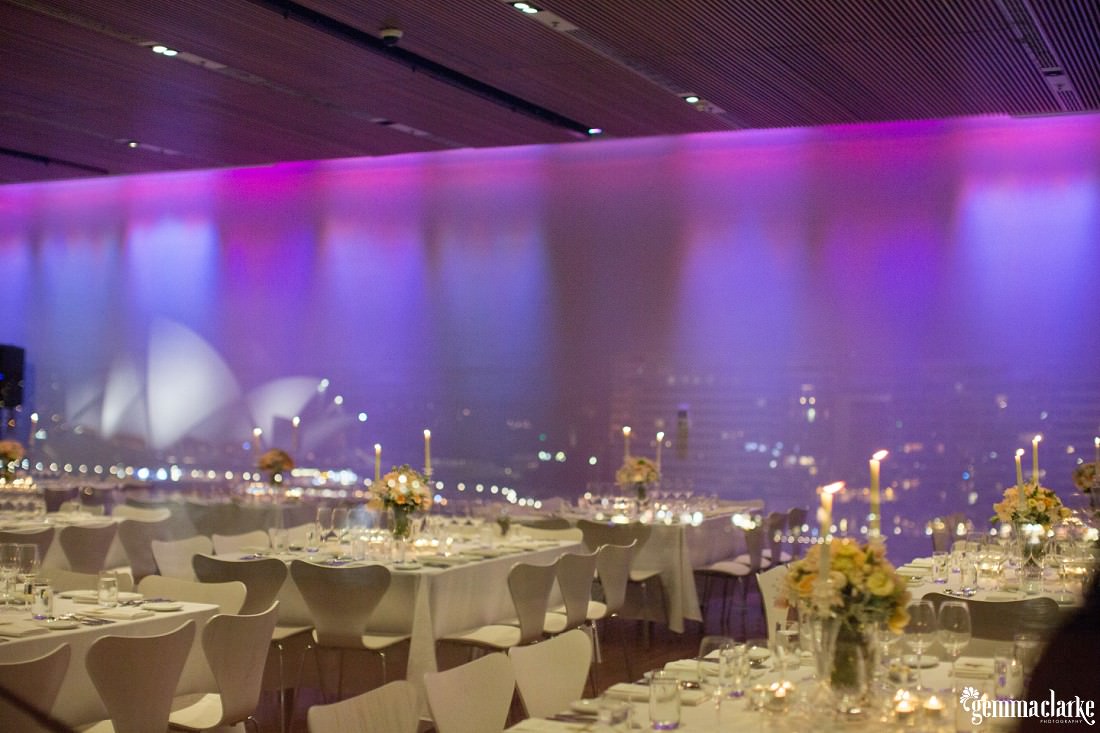 A wedding reception setup in the Museum of Contemporary Art with the reflection of the Sydney Opera House in the window - Sandstone Sydney Wedding