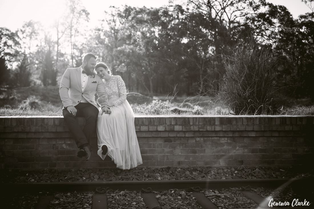 Sitting by the train tracks and having a giggle while the sun warms them up at their Buxton Wedding